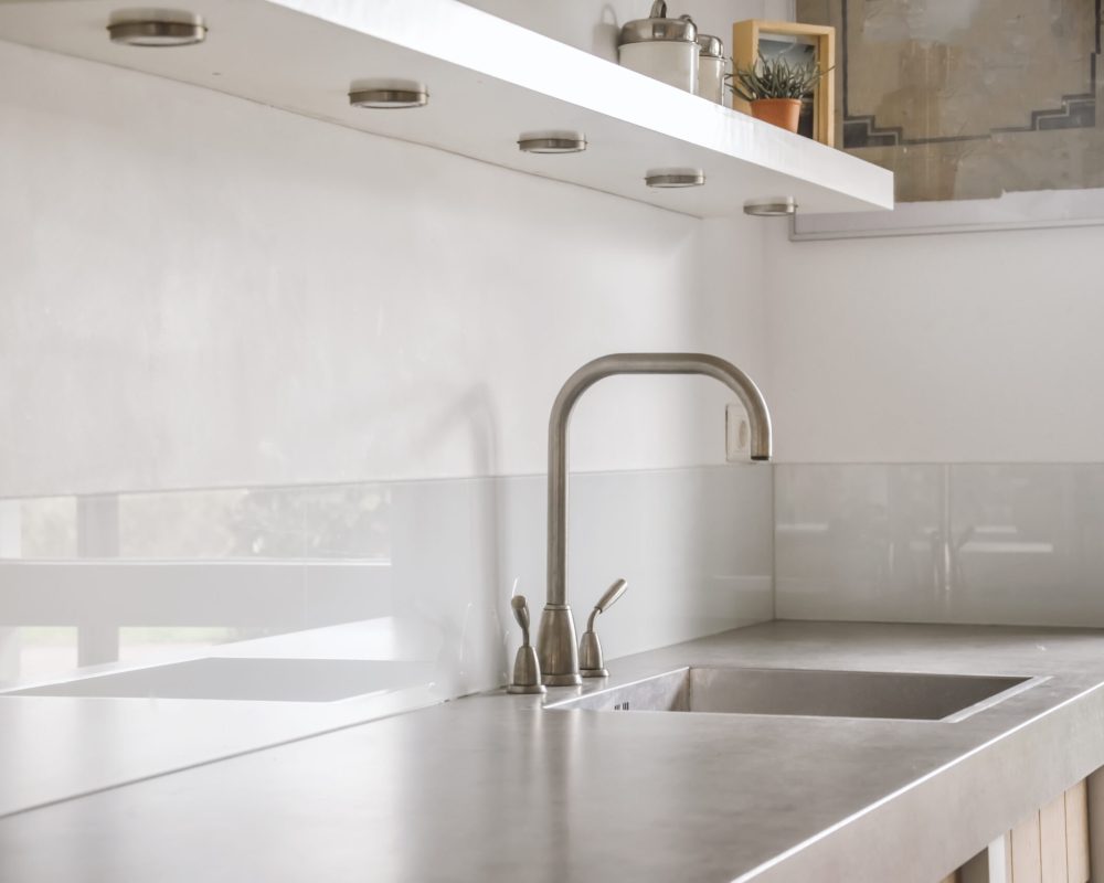 Glassplate bak kjøkkenbenk i lyst kjøkken med stilrent uttrykk